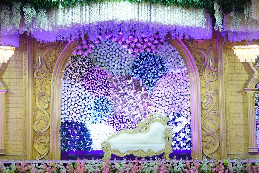 A white chaise set in front of a floral wedding stand