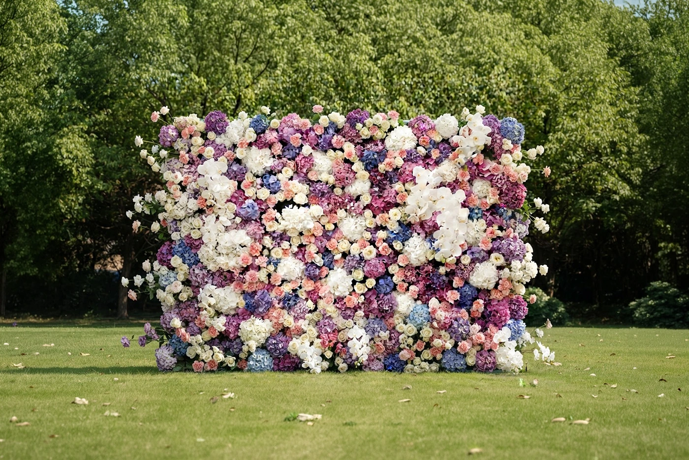 A floral wall of white, blush, lilac and blue blooms standing on a lawn