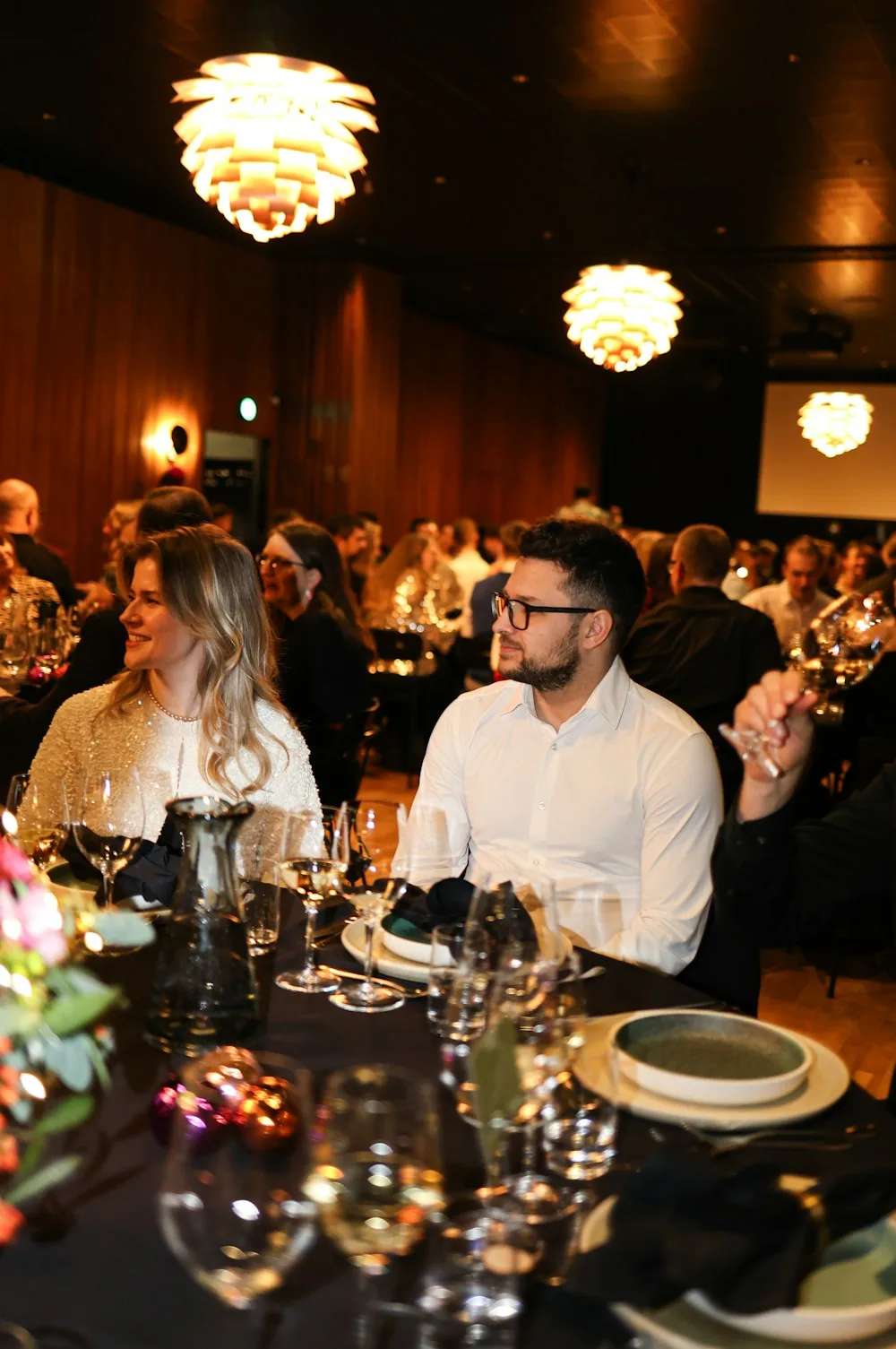 Guests seated under warm light at a formal dinner