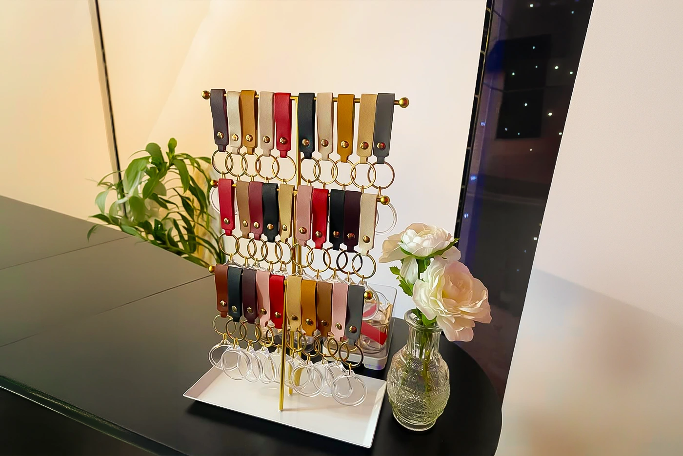 Rows of leather keychain fobs in cream, tan, red and black hanging from a gold display stand