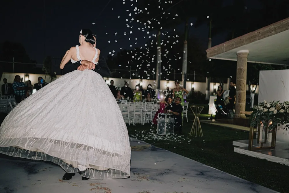 A couple dancing under falling petals after dark