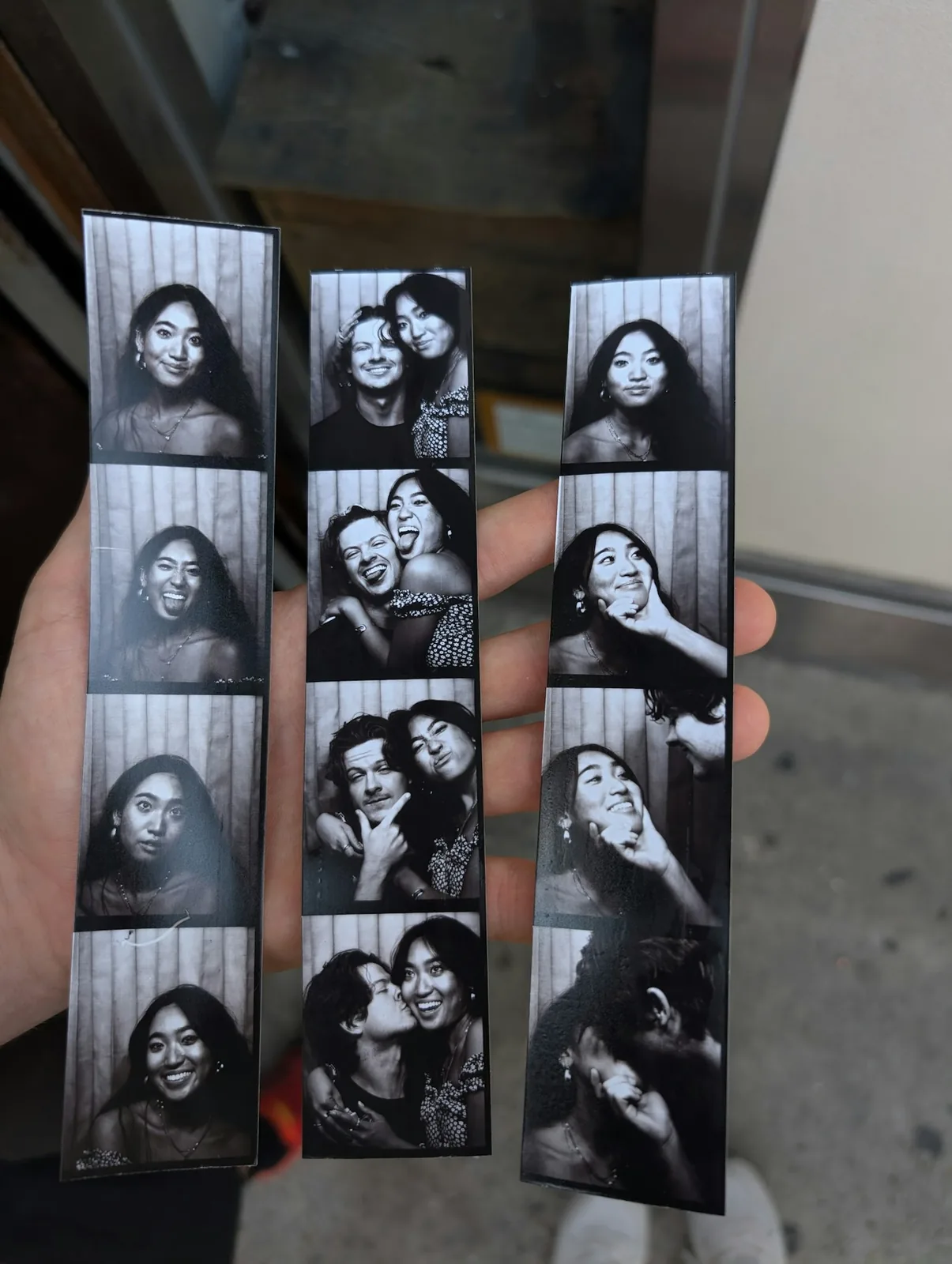 A hand holding three finished photo strips