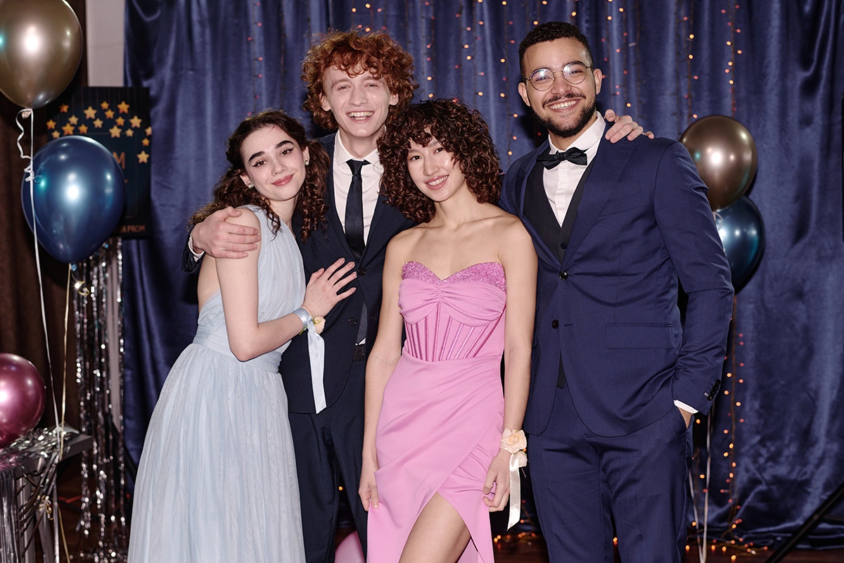 Four students in formalwear posing together with balloons at prom